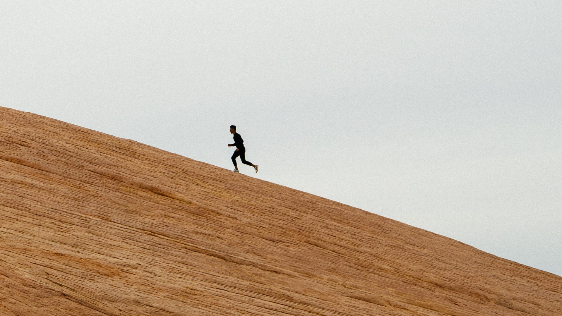 A lone man running up a vast sunlit ridge